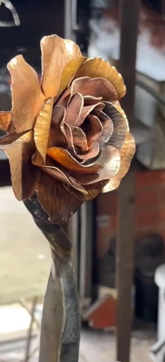 A copper rose, petals raised and peened