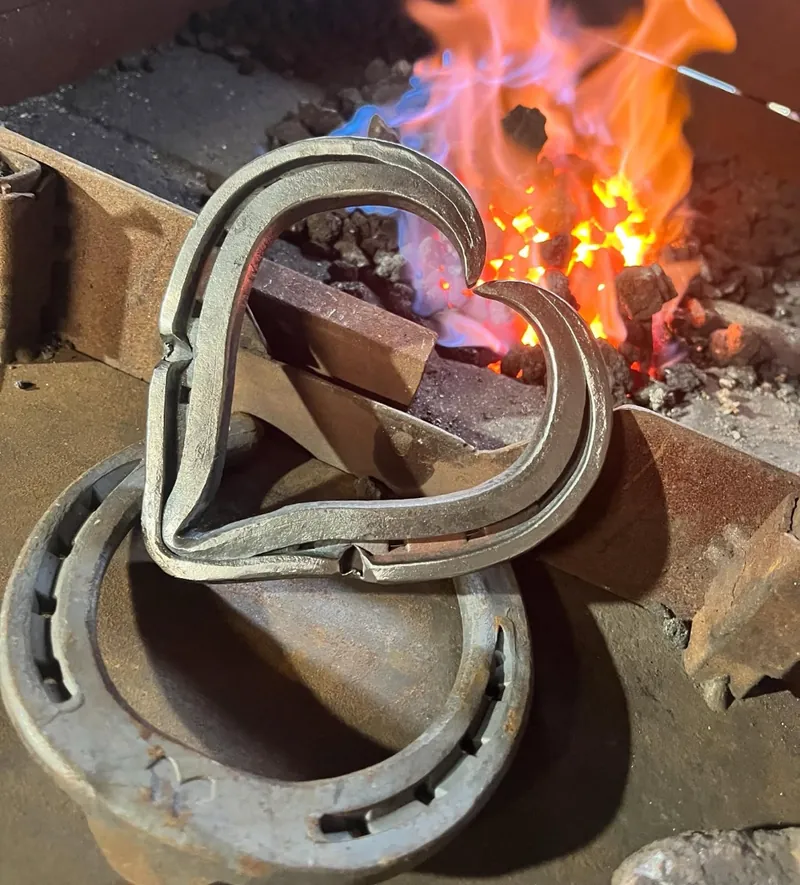 A heart forged from two horseshoes, resting in front of the fire