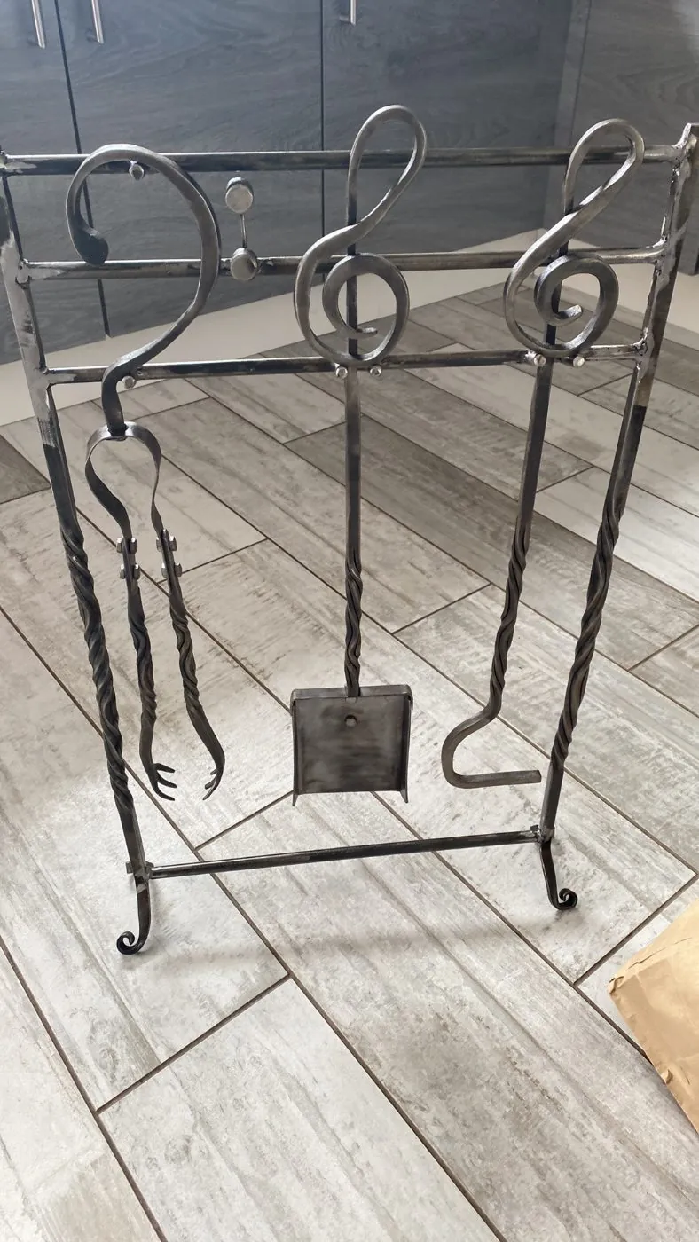 A fire tool set with treble clef handles, in mild steel