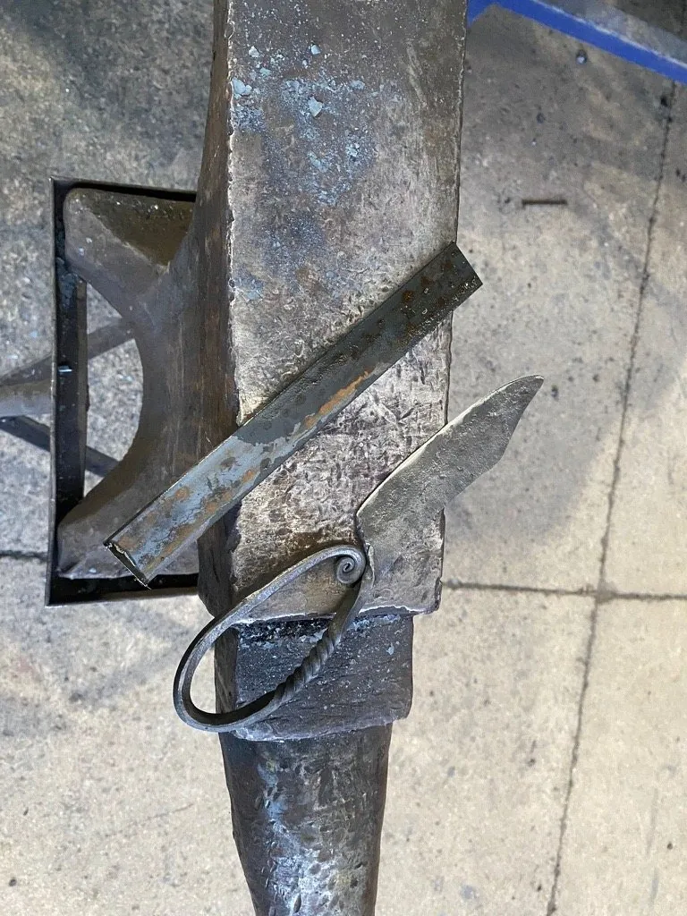 The knife forged at Oldfield Forge, resting across the anvil