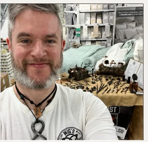 Wig in a white Wonky Forge t-shirt at an early market stall, the first pieces laid out on burlap behind